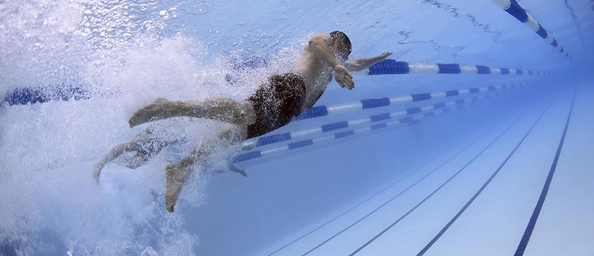 En person simmar i bassäng med luftbubblor runt benen.