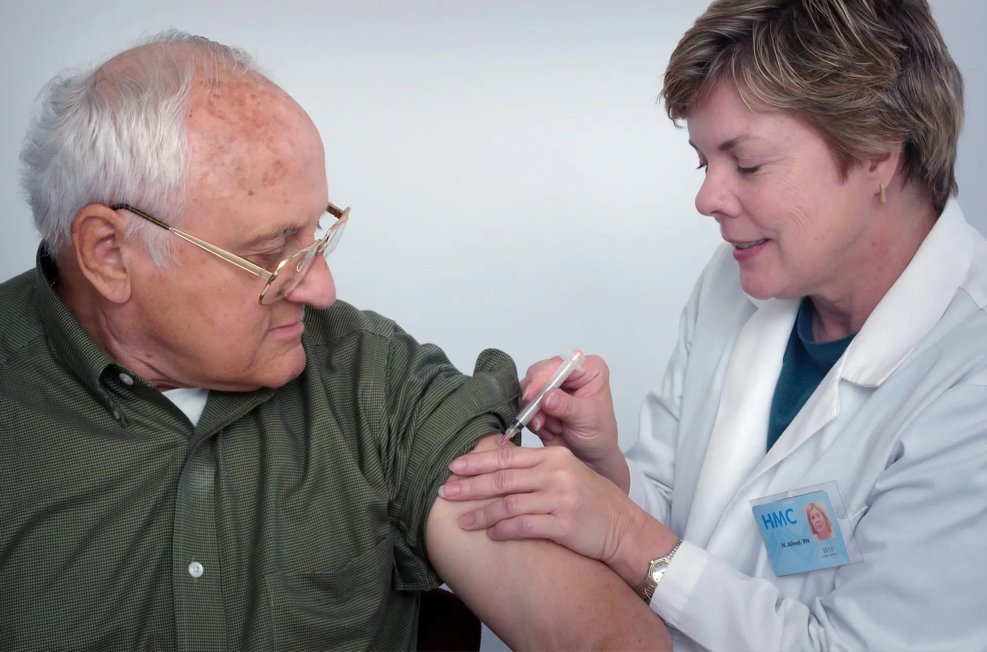hemsjukvård. Läkare sticker spruta i armen på äldre person